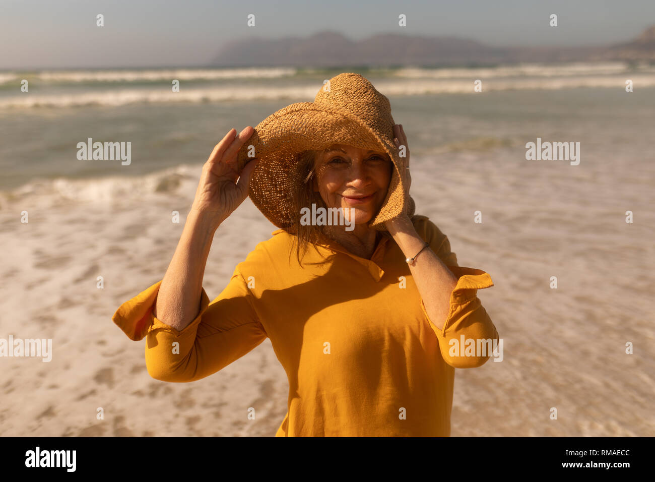 Active senior woman in hat standing on the beach Stock Photo - Alamy