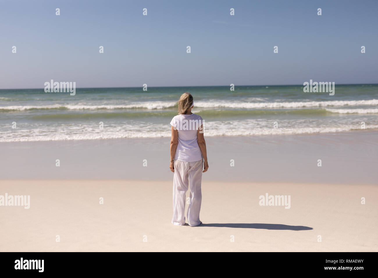 Rear view of senior woman standing on the beach Stock Photo - Alamy
