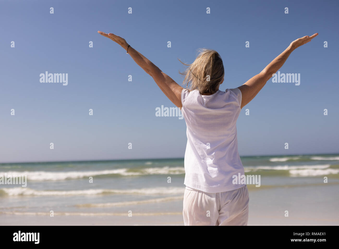 Rear view of senior woman standing with arms outstretched at beach Rear view of senior woman standing with arms outstretched at beach