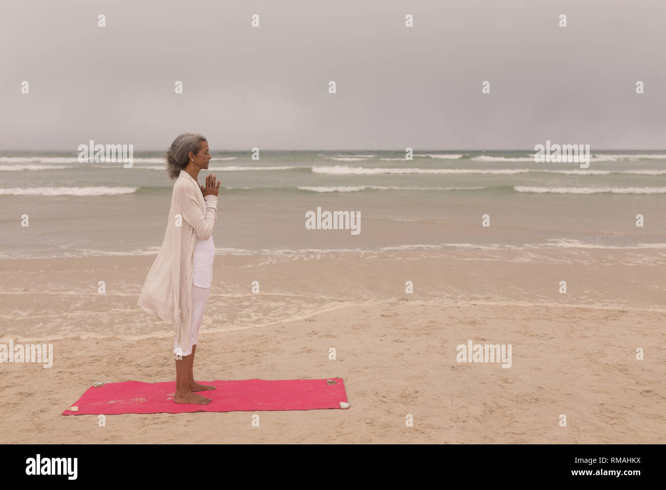 Senior woman with eyes closed and hands clasped doing yoga on the beach Stock Photo Alamy
