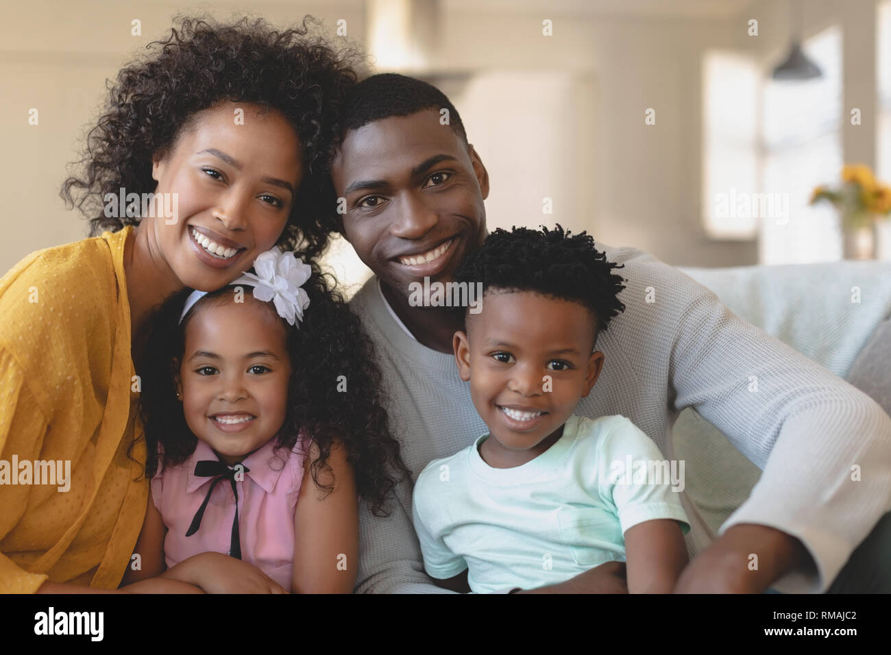 Happy African American family sitting on sofa and looking at Stock Photo