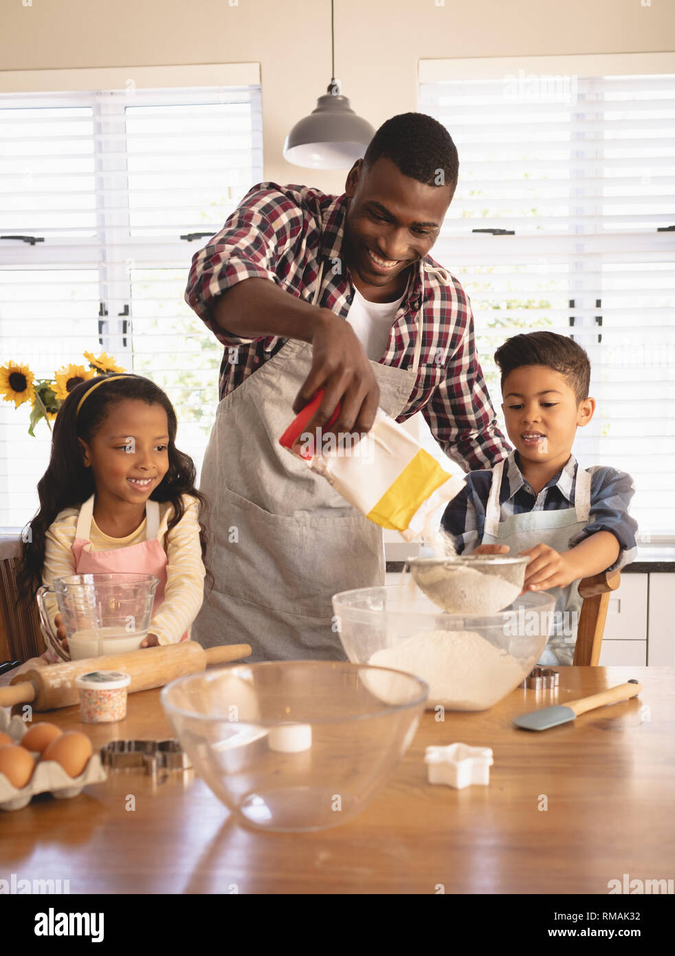 African American father and children baking cookies in kitchen Stock Photo