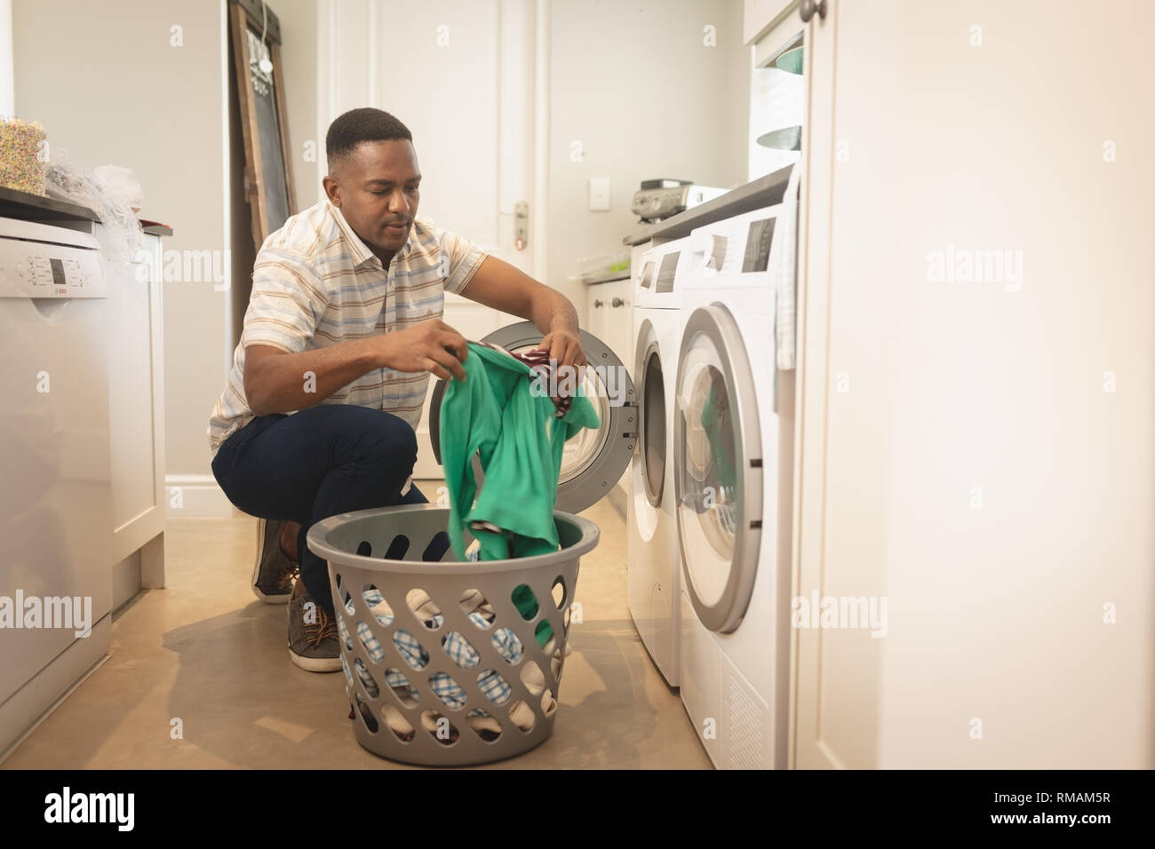 African American man washing clothes in washing machine Stock Photo