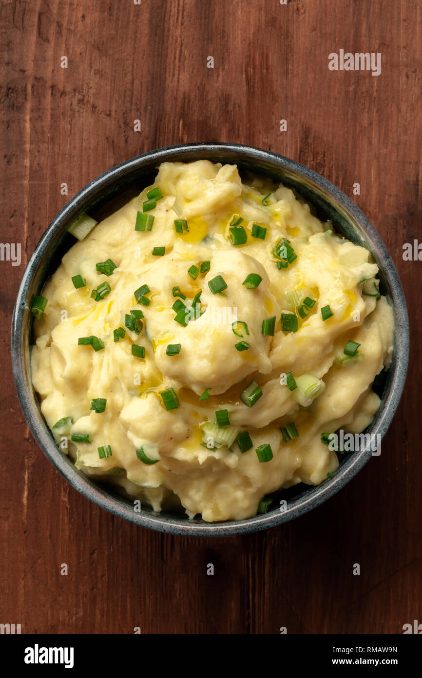 Pomme puree, a photo of a bowl of mashed potatoes with scallions, shot from the top on a dark rustic background with a place for text Stock Photo