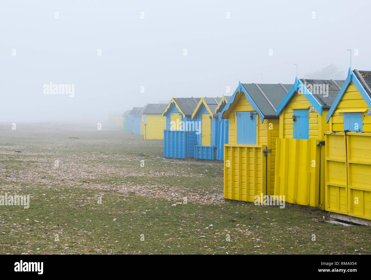 Beach huts in misty foggy conditions on a deserted beach in Winter on a beach in the UK. Stock Photo