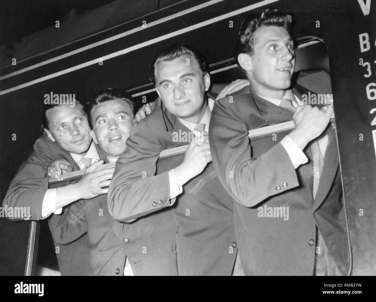 Arrival of the crew at the station in Lindau.Players of the team lean out of the train window. From left: Max Morlock, substitute, Jupp Posipal, Hans Schaefer. In 1954 Germany won its first World Cup in Switzerland. Stock Photo