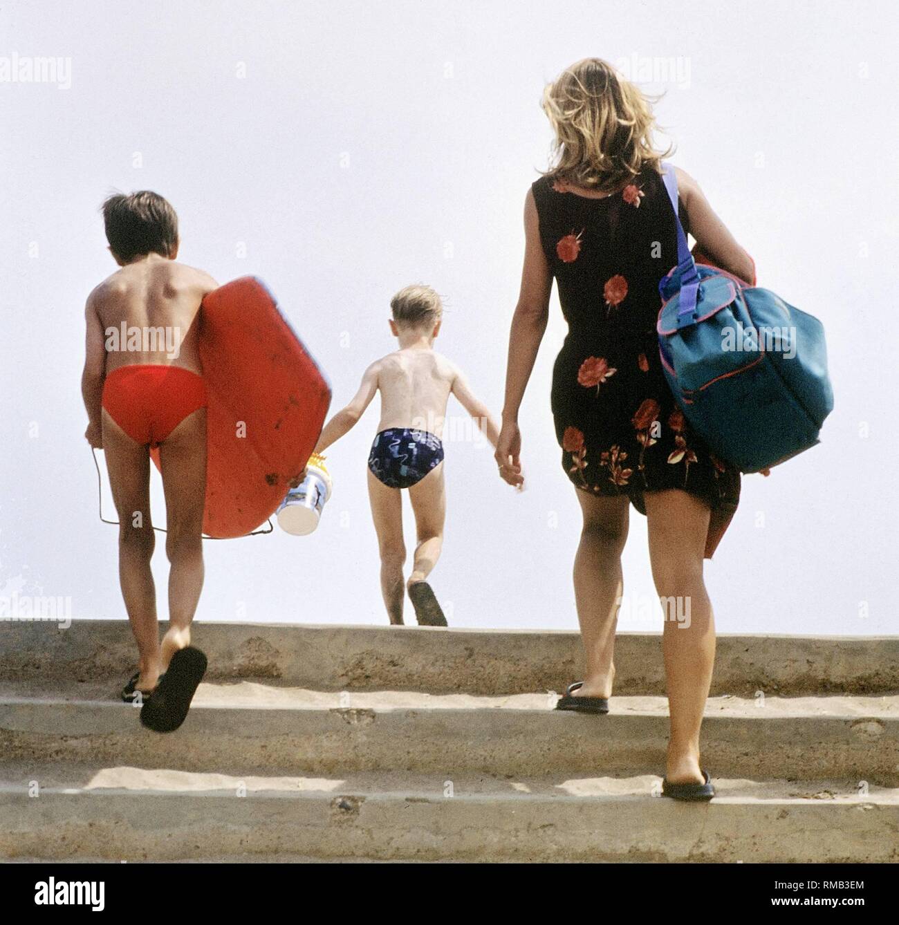 A woman is on her way to the beach with her two boys. Stock Photo