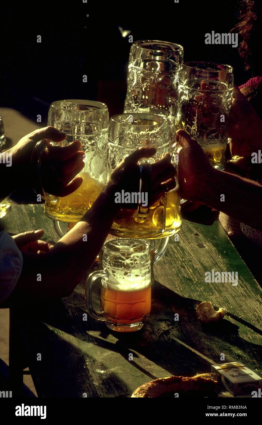 Guests toasting with their beer mugs at the beer garden at the Chinese Tower in the Englischer Garten. Stock Photo