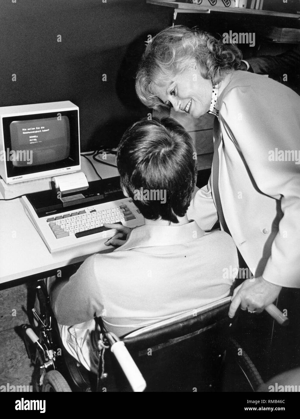 The President of the Kuratorium ZNS, Hannelore Kohl with a patient in the Eifelhoehen KliniK in Nettersheim-Marmagen in front of a so-called 'brain jogger'. The the machine with which the patient trains was donated by the Kuratorium ZNS (today ZNS - Hannelore Kohl Stiftung fuer Verletzte mit Schaeden des Zentralen Nervensystems - Hannelore Kohl Foundation for the injured with central nervous system damage). Stock Photo