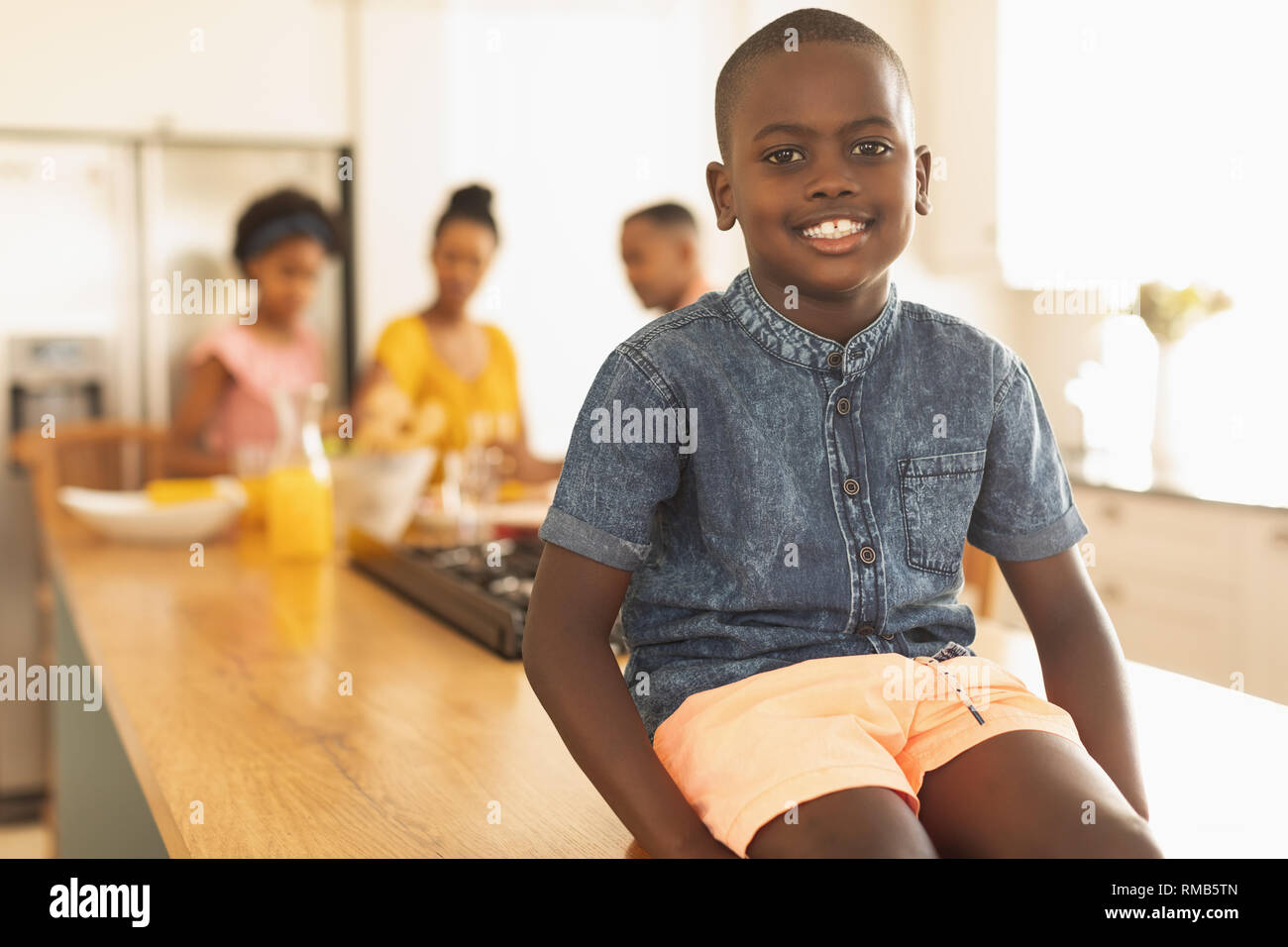 Happy African American boy sitting on dining table Stock Photo