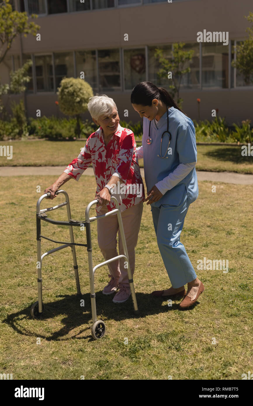 Young female doctor helping disabled senior woman in garden Stock Photo