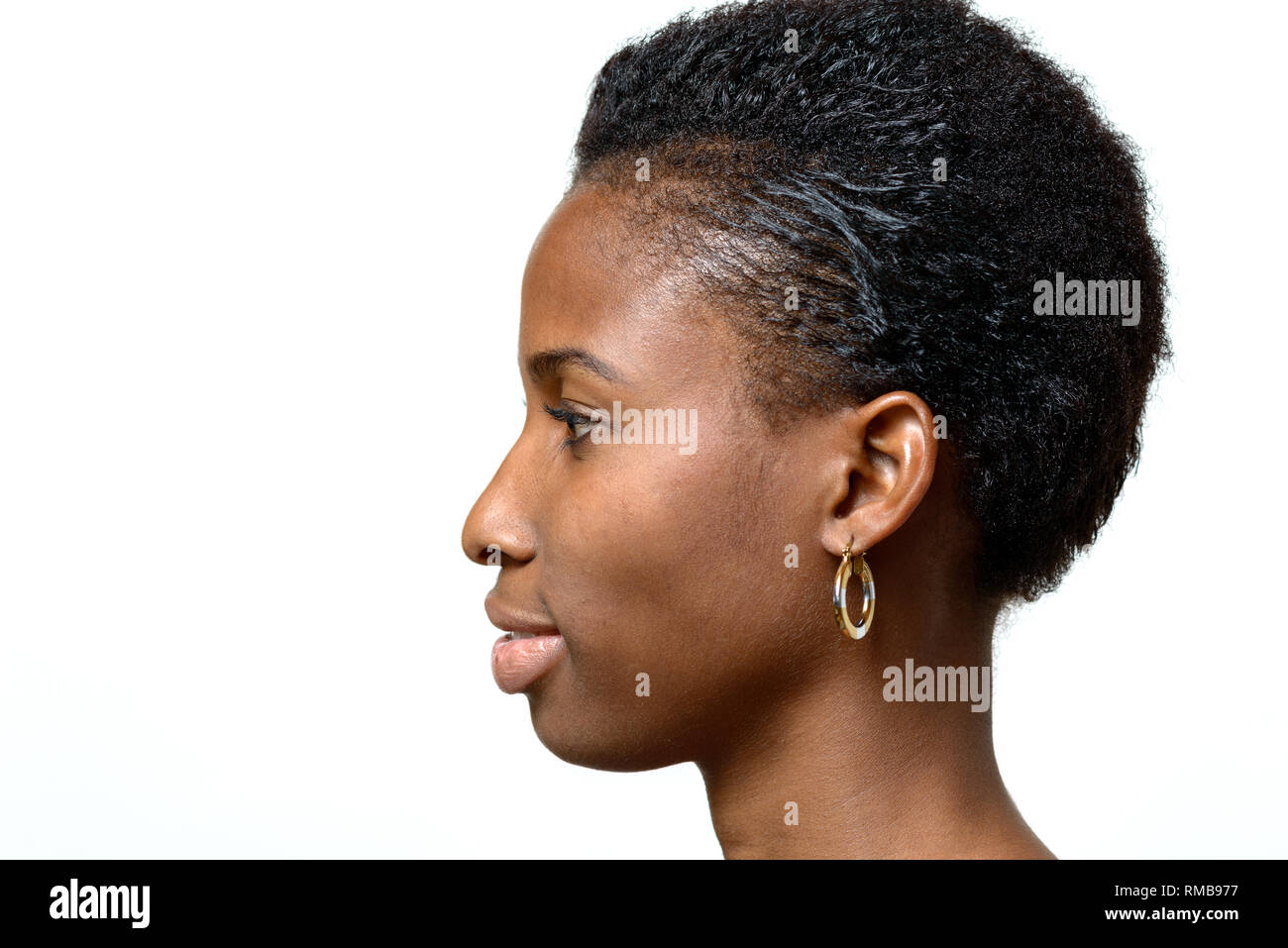 Profile portrait of an attractive African woman with a quiet smile and a neat short hairdo facing blank copy space over white Stock Photo