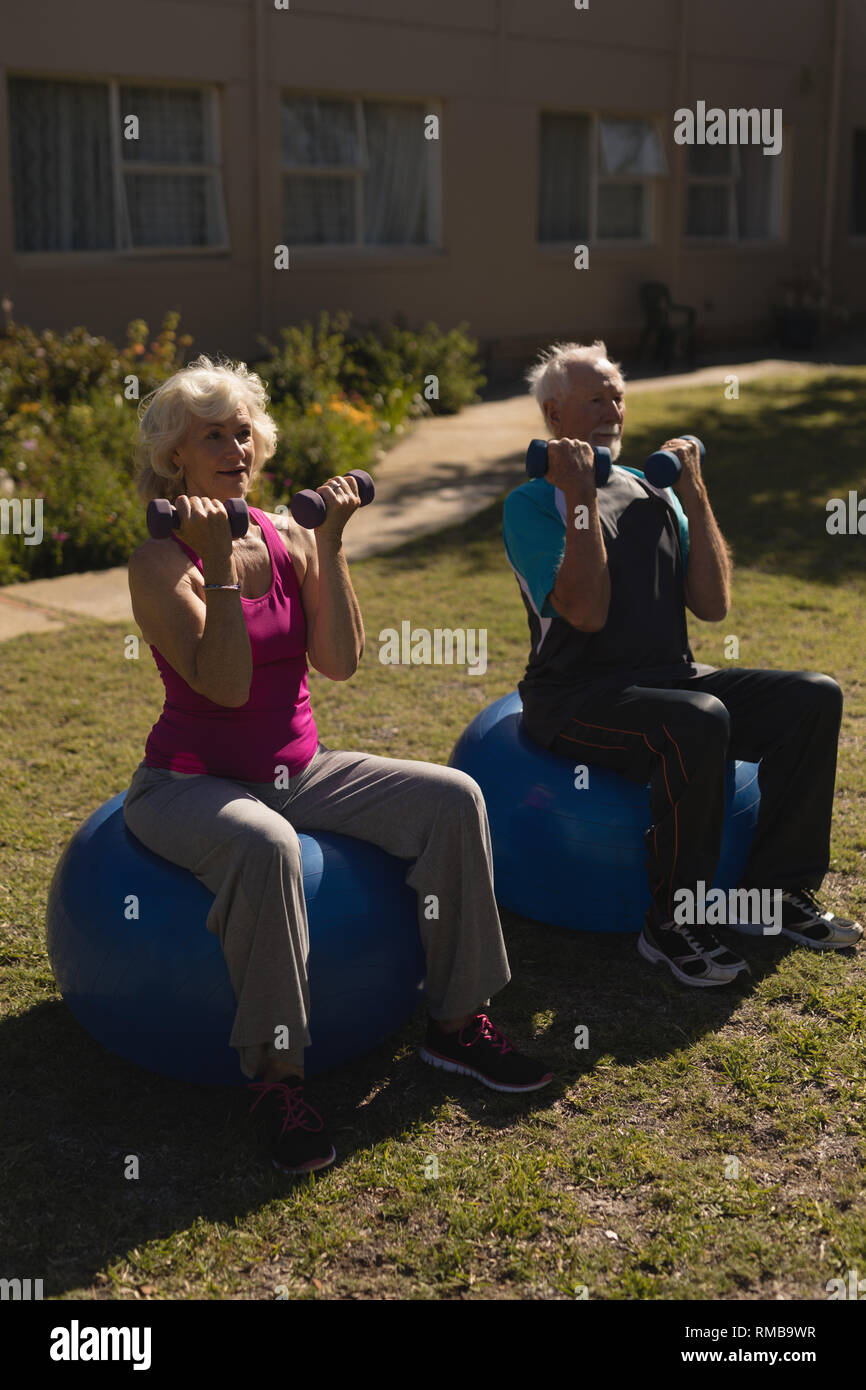 Senior couple exercising with dumbbells in the park Stock Photo