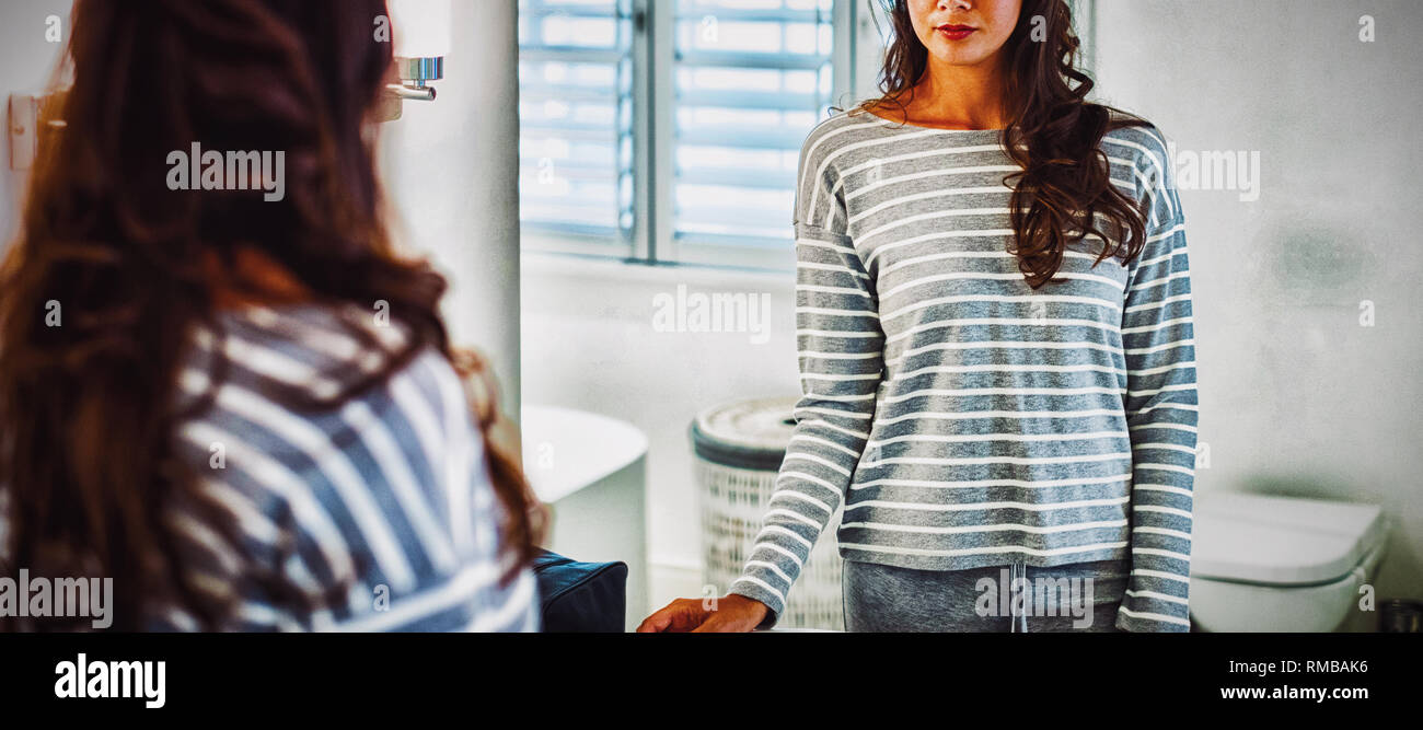 Woman looking at herself in the bathroom mirror Stock Photo