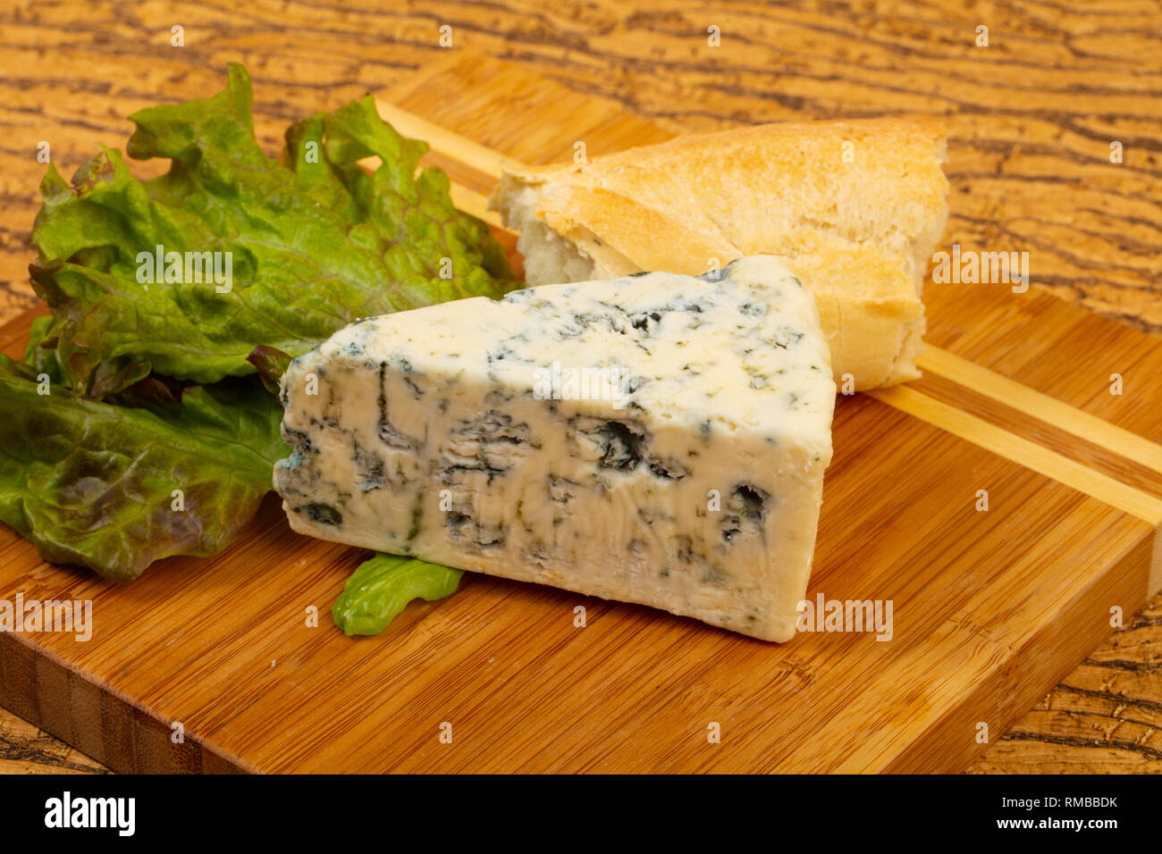 Blue cheese with salad leaves over board Stock Photo Alamy