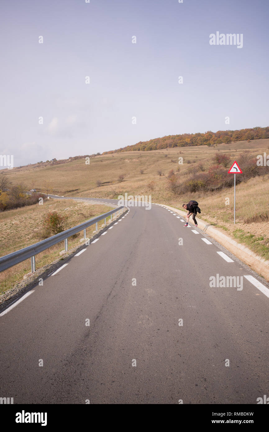 A man stands on the side of the side of an empty road on Strada Hoia in ...