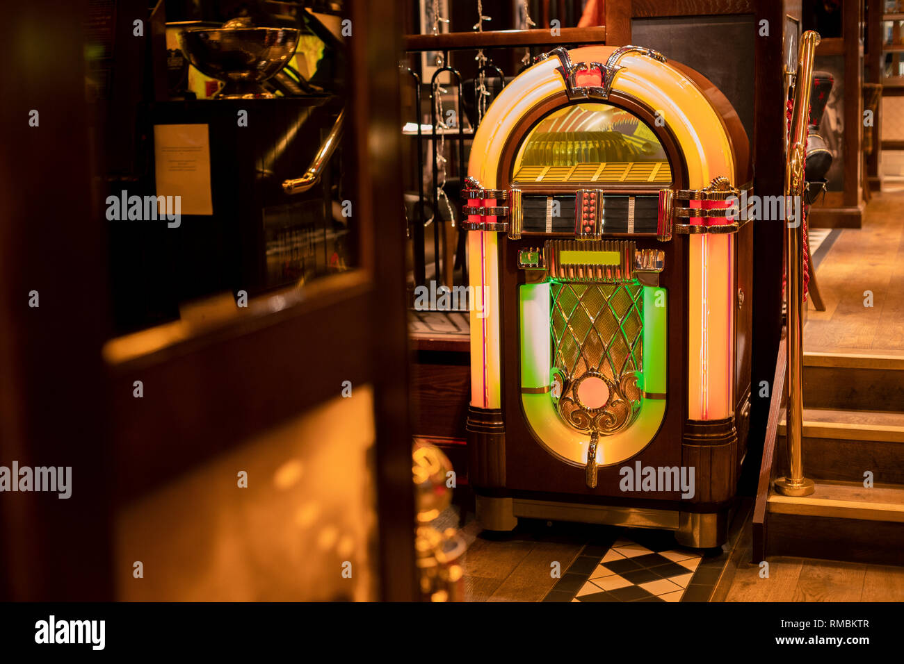 Retro jukebox in the corner of a restaurant by a set of stairs. Stock Photo