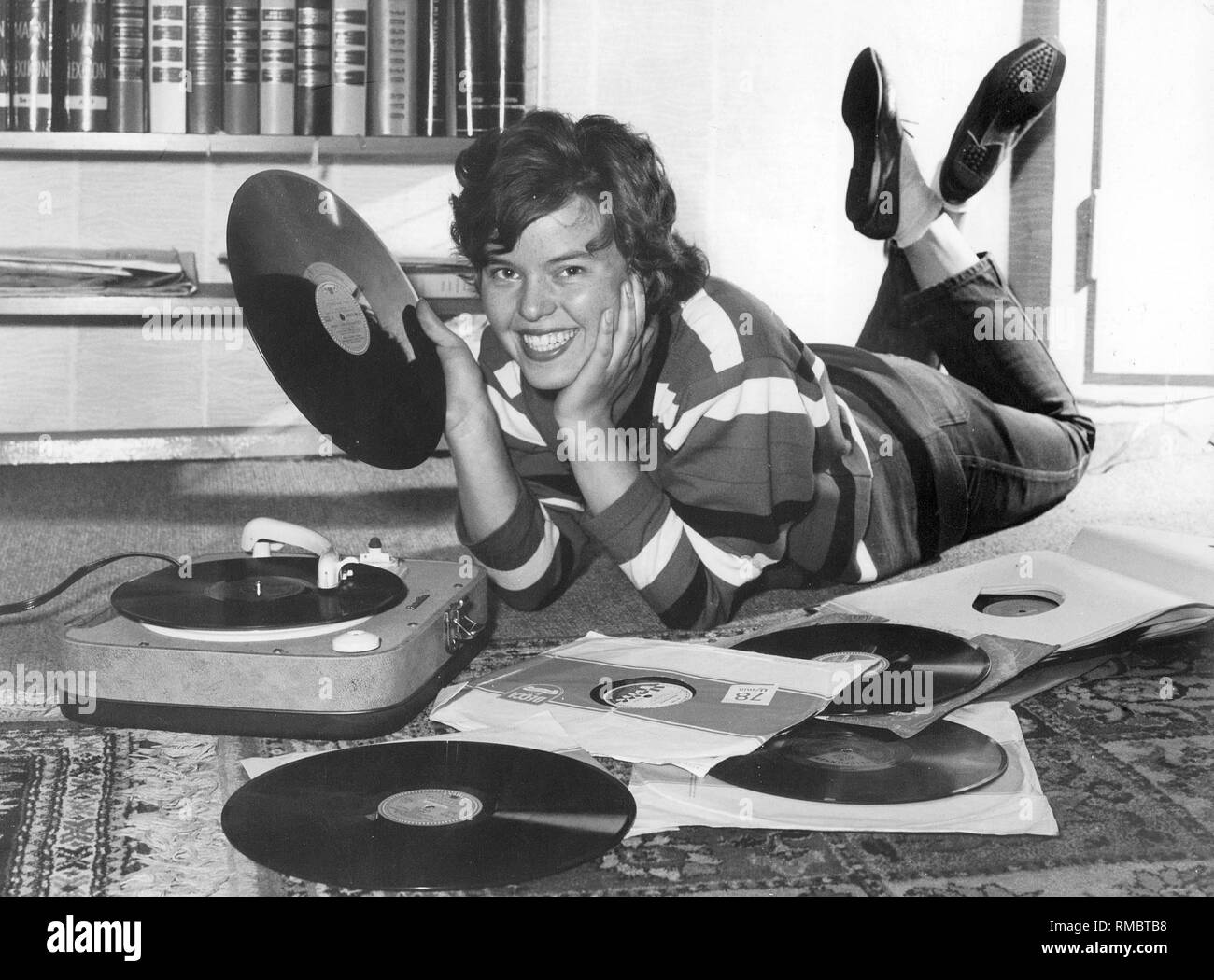 A young woman is listening to vinyl records. Photographer: Pretzl. Stock Photo