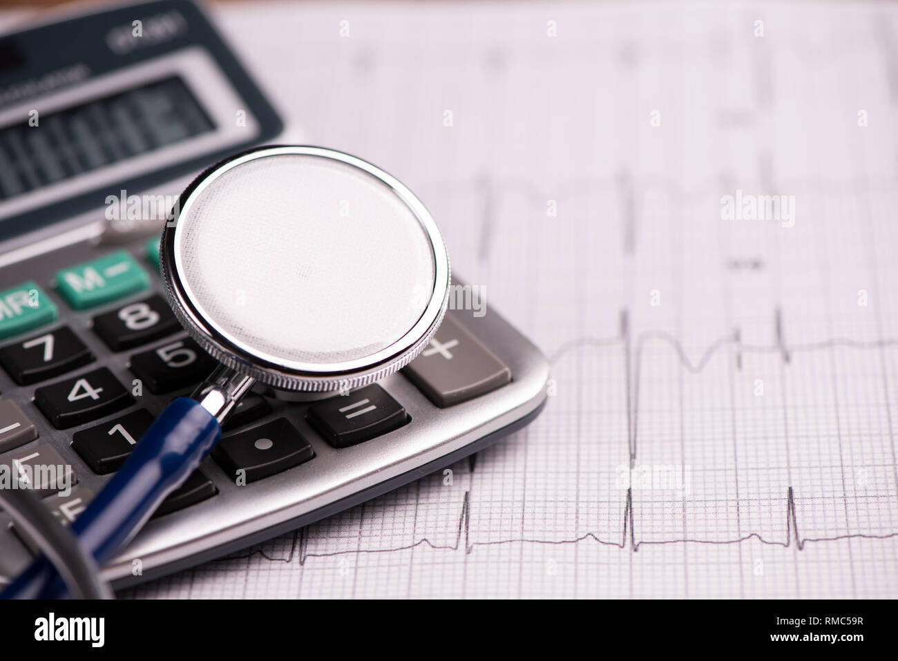 EKG with  stethoscope and calculator showing cost of health care. Close up Stock Photo