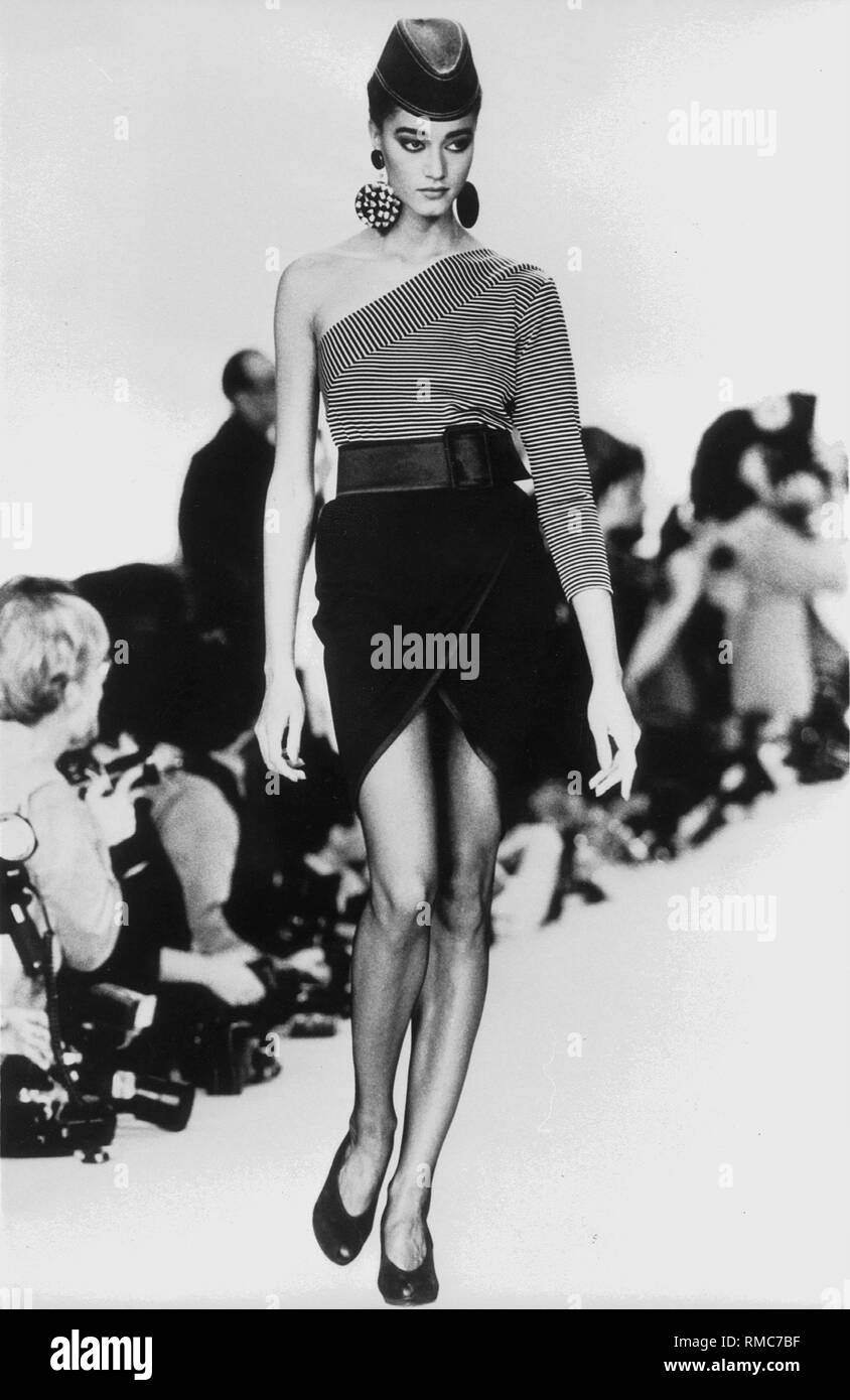 A model presents a costume by Yves Saint Laurent for the summer fashion  1987 at a fashion show in Paris. The model wears a combination of a  strapless striped shirt and a