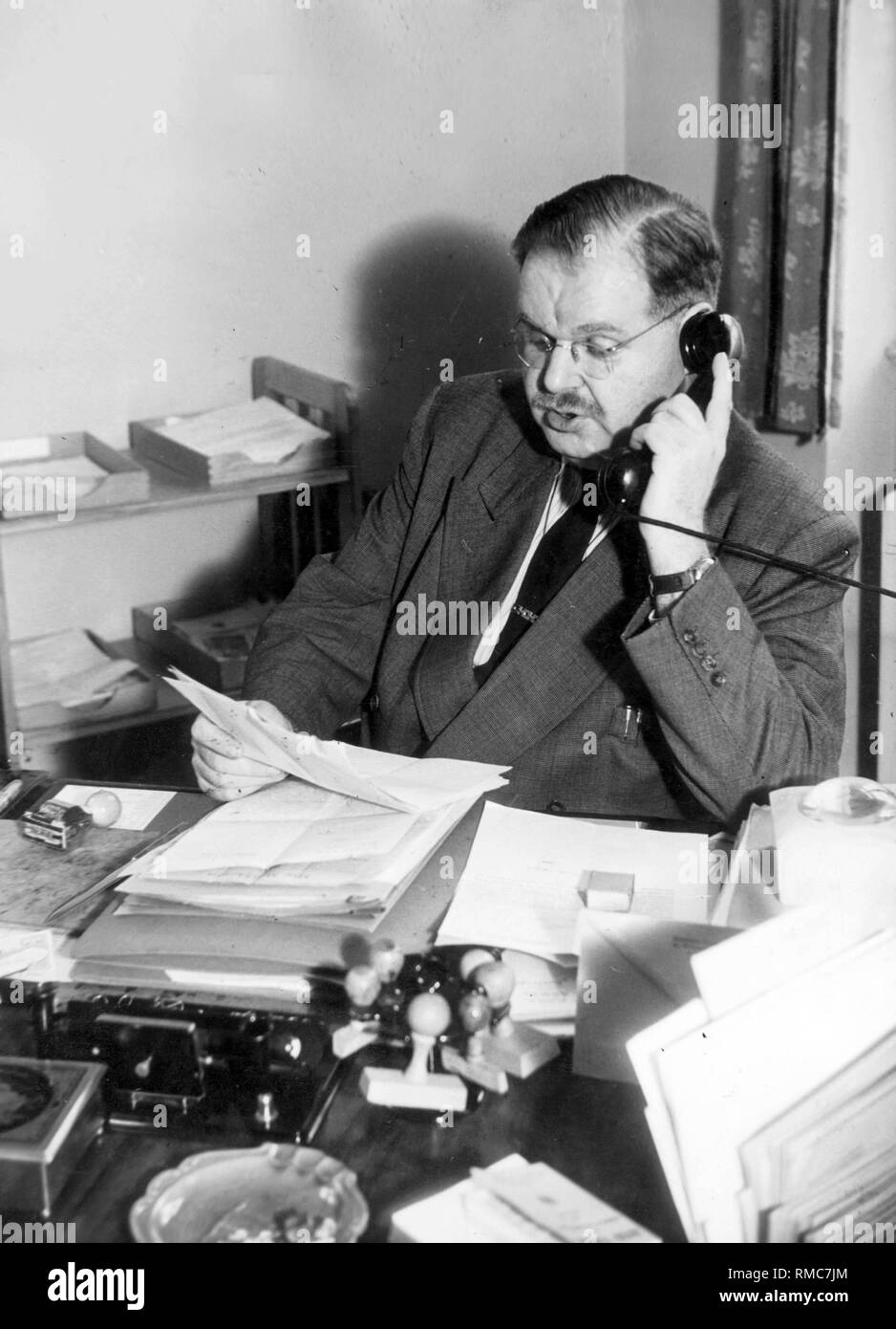 Philipp Auerbach (1906-1952), President of the Landesentschaedigungsamt (Land Compensation Office), telephones in his office. Undated image, probably around the year 1950. Stock Photo