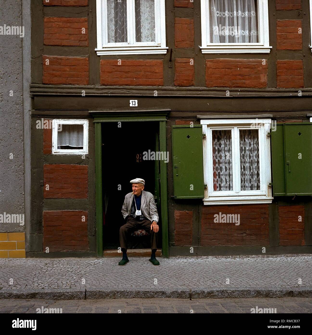 A Man Sits At His Doorstep In The Small Town Of Werben Elbe Stock