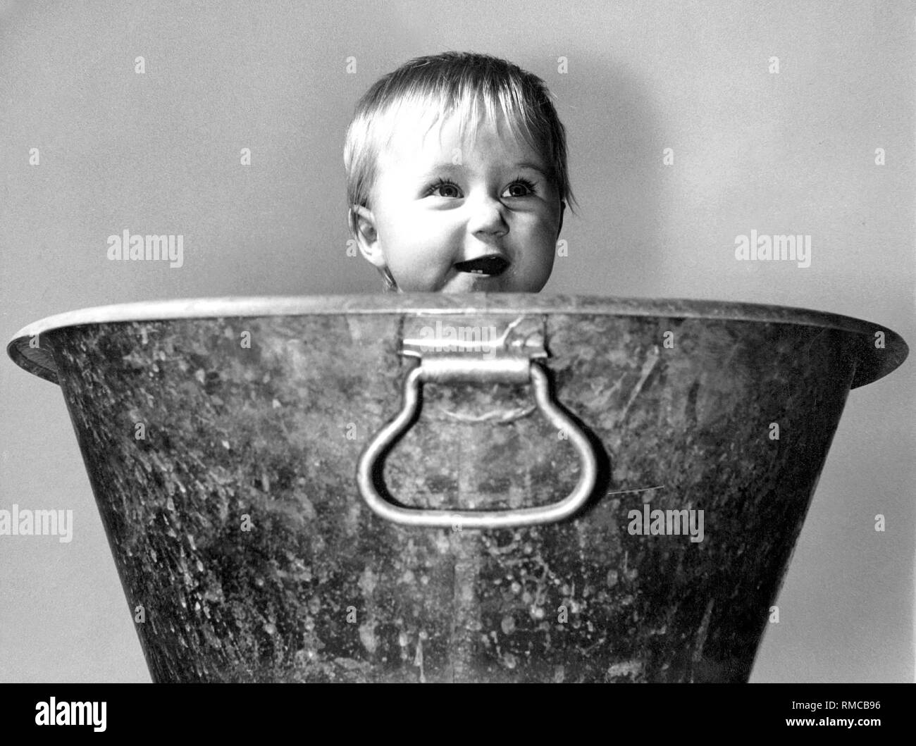 Child sitting in a tin bathtub. Stock Photo