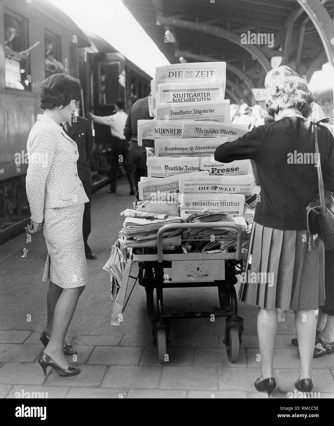 Women look at newspaper issues in the cart of a mobile newsagent, Stock Photo