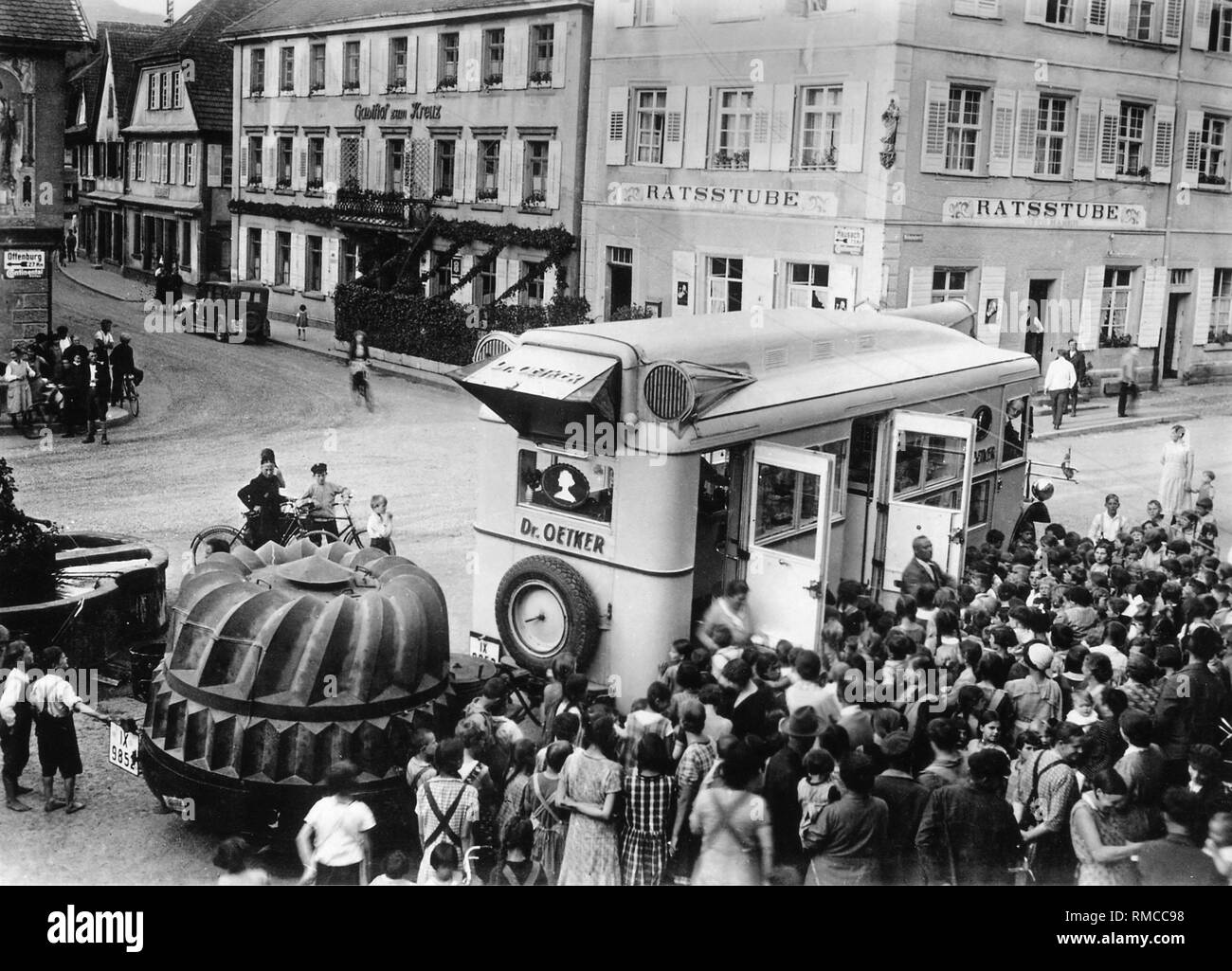 When there was no radio and television advertising,  advertisements had to be made locally: In the 30s of the last century Oetker sent his rolling bakeries throughout the country. Contemporary loudspeaker calls attracted the customers, certainly also because one could try the fresh cookies immediately. The huge cake-pan (for a 'Gugelhupf') on the trailer contained a technical sensation of that time. It had a generator that provided electricity for the baking demonstrations. Stock Photo