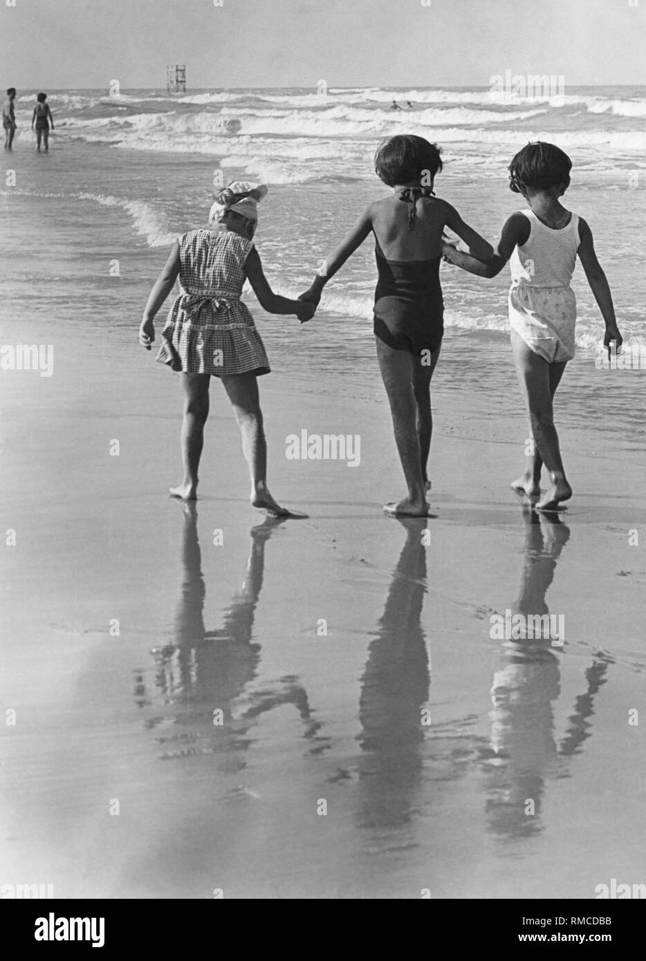 Three girls during a beach walk, 50s Stock Photo