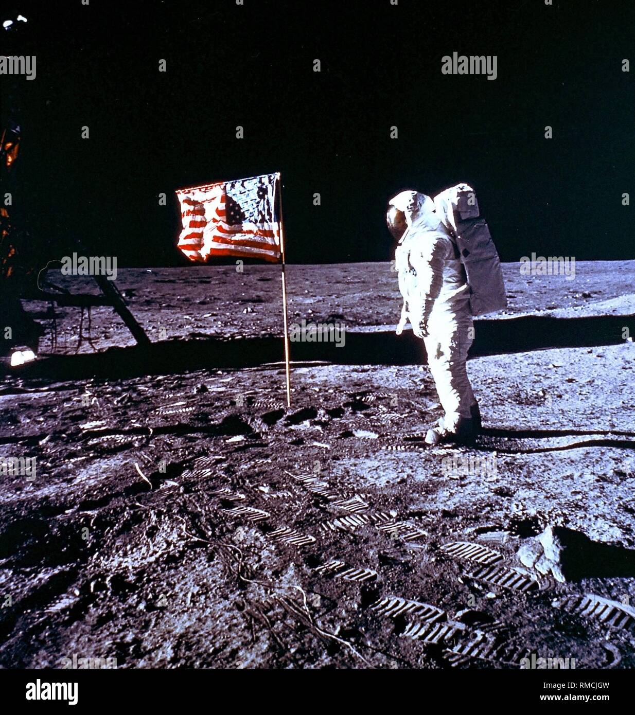 Edwin 'Buzz' Aldrin, the second man on the Moon and commander of the Apollo 11 Lunar Module 'Eagle', walking on the Moon in front of the US flag. Apollo 11 was the first manned Moon landing mission, with that the most significant space mission for humanity. Stock Photo