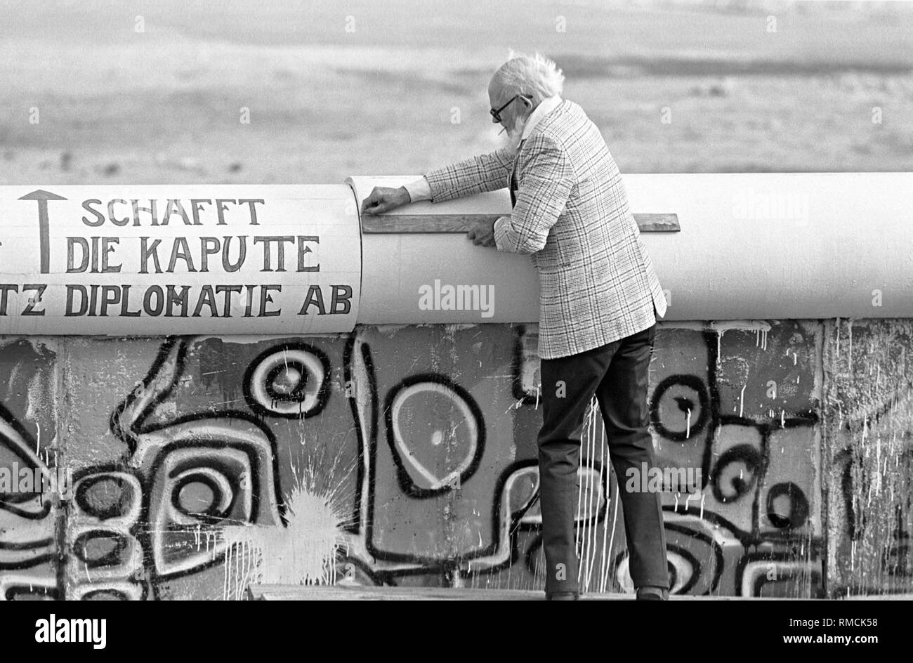 The American anti-Wall activist John Runnings mounts slogans at the top of  the Wall. Potsdamer Platz Stock Photo - Alamy