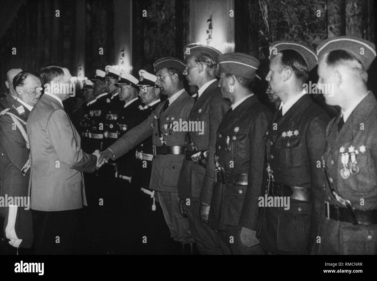 Adolf Hitler (behind Hermann Goering) welcomes soldiers of the Wehrmacht with a clasp at a reception in the Reich Chancellery. They belong to the contingent deployed in the Spanish Civil War. Stock Photo