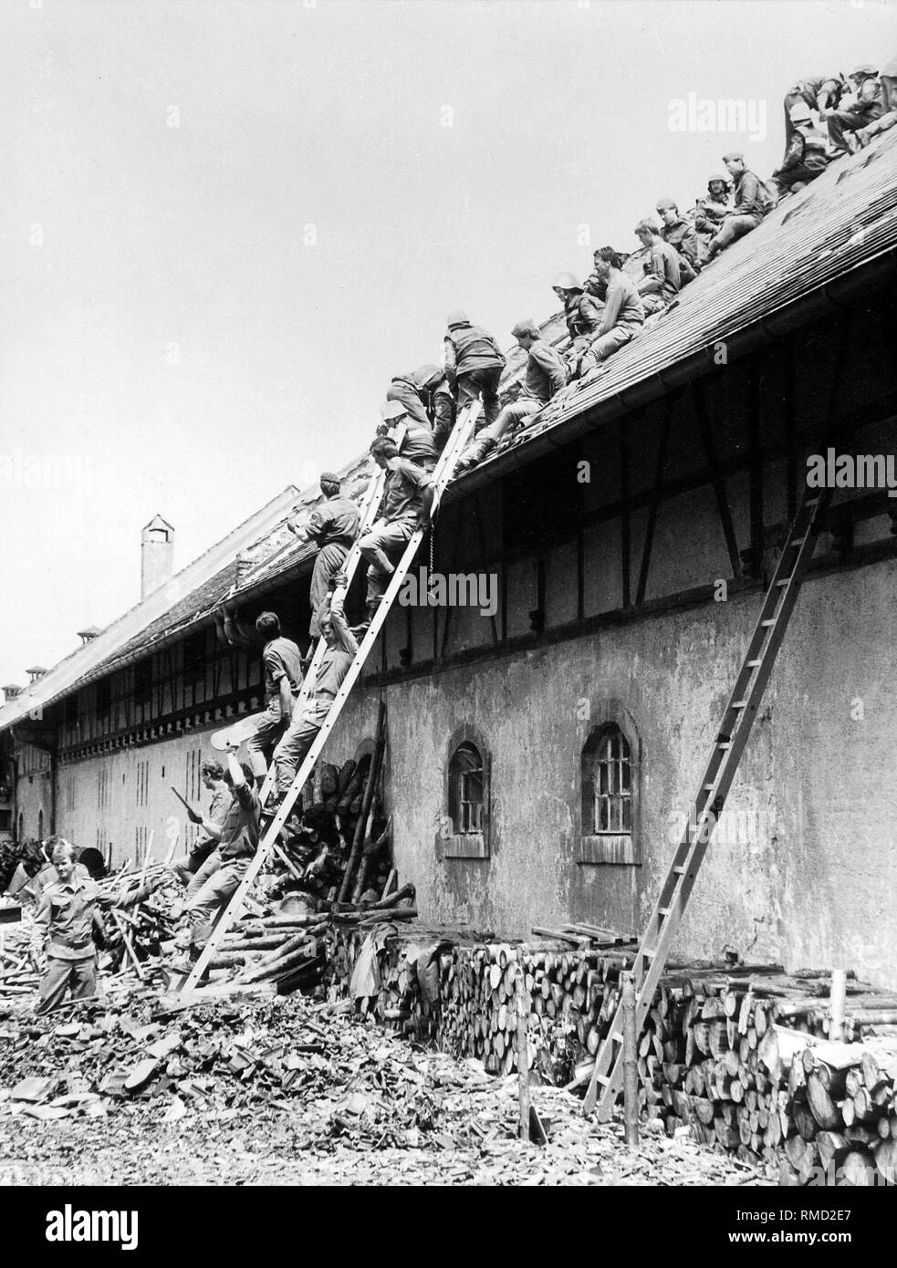 Soldiers of the Bundeswehr University in Neubiberg help repair the hail damage, here on the roof of a barn on the estate of the Haars. Stock Photo