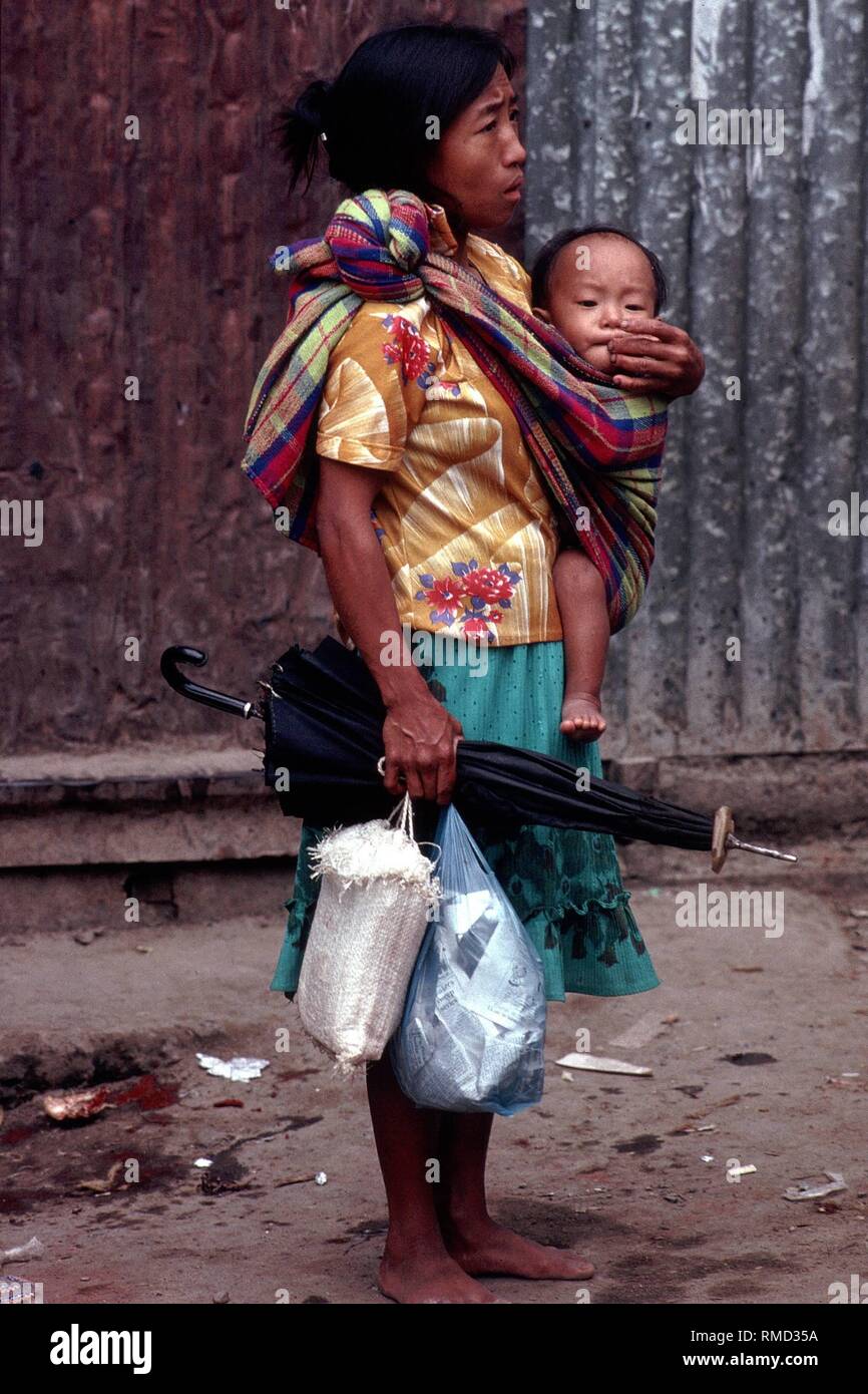 On the southern Leyte lies the small town of Banaue, which once a week houses a large market. Here a mother carries her little child in a front carrier. Stock Photo