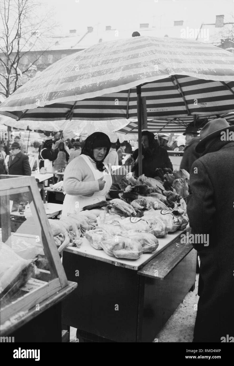 View of a market woman at a stall selling meat and poultry on the Munich Viktualienmarkt. Stock Photo