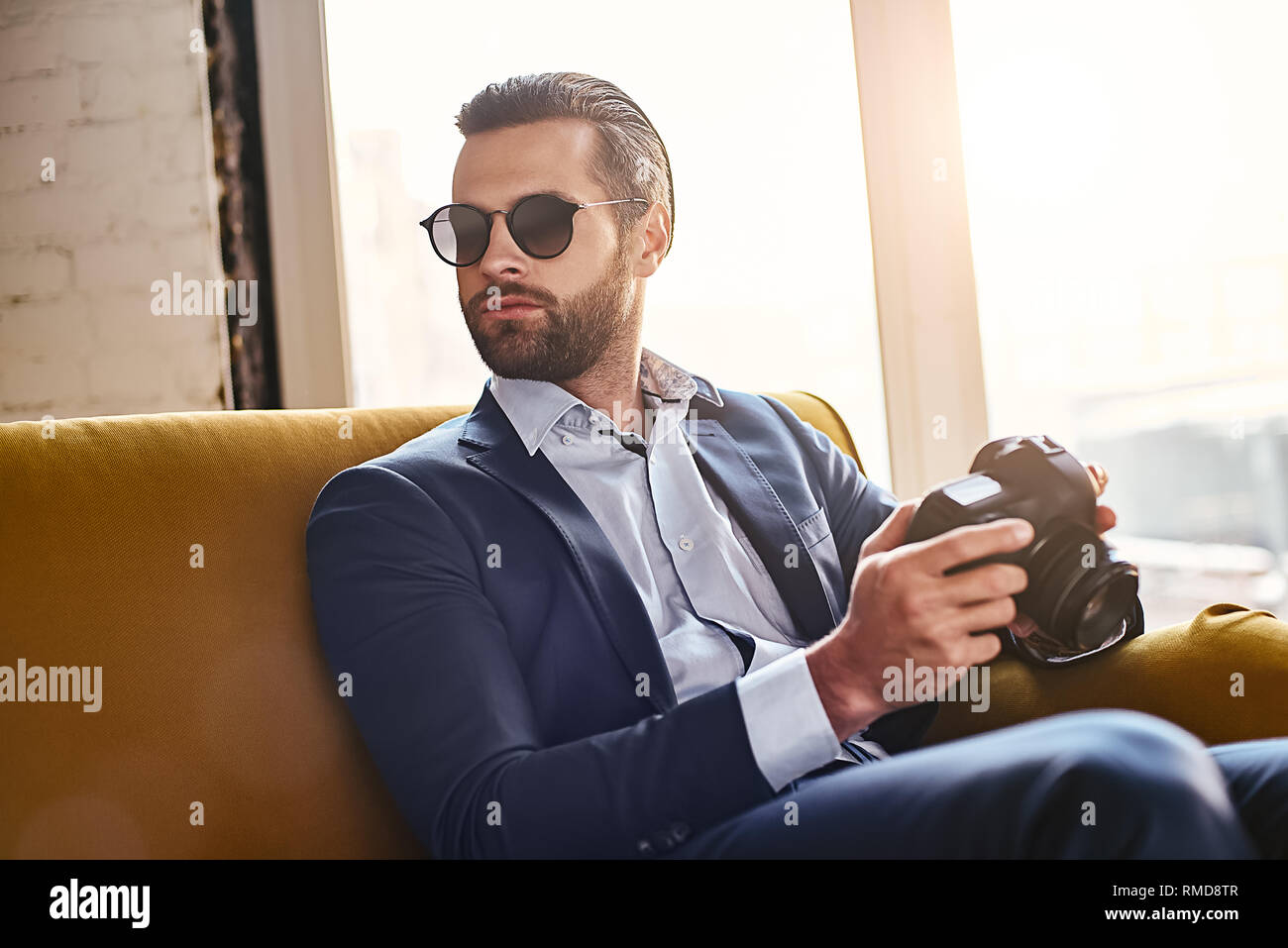 In search of inspiration. Successful young stylish businessman in sunglasses, is holding photo camera and thinking about something. Business style. Fashion look Stock Photo