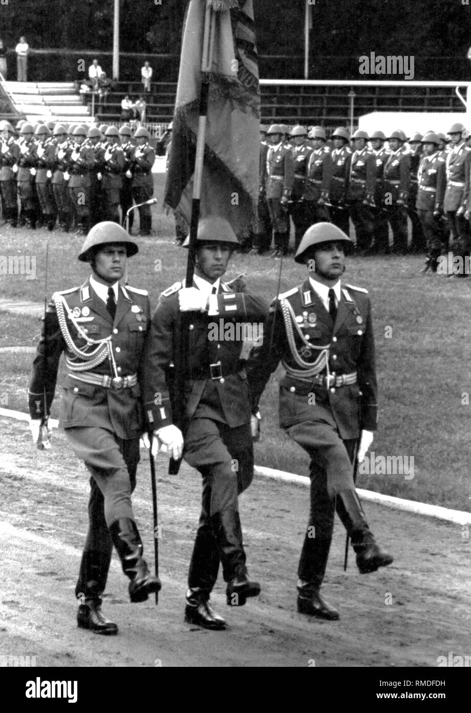 Military ceremonial on the occasion of the swearing-in of graduates of the Offiziershochschule 'Ernst Thaelmann' of the Land Forces of the National People's Army (NVA) of the GDR in Loebau, parade with troop flag of the OHS. Stock Photo