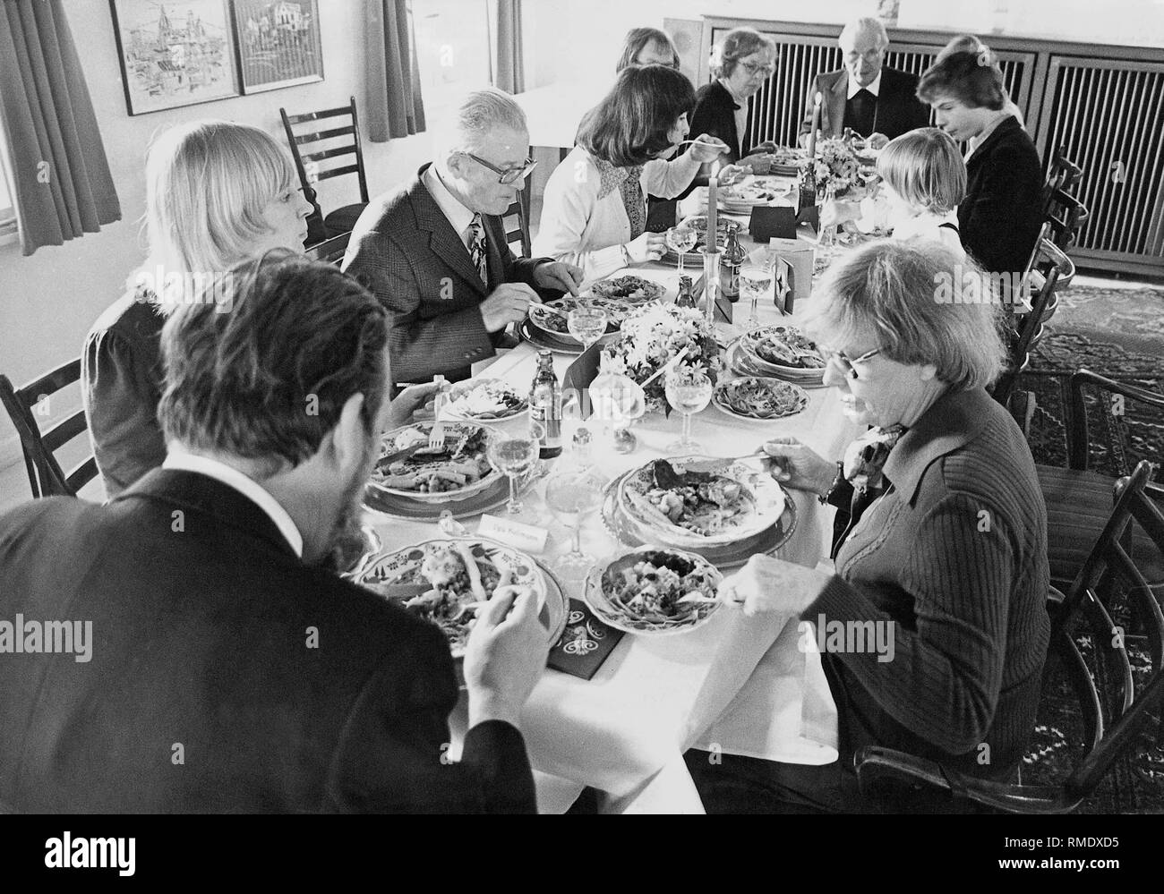 A family sits around a long table at a festive meal. Stock Photo