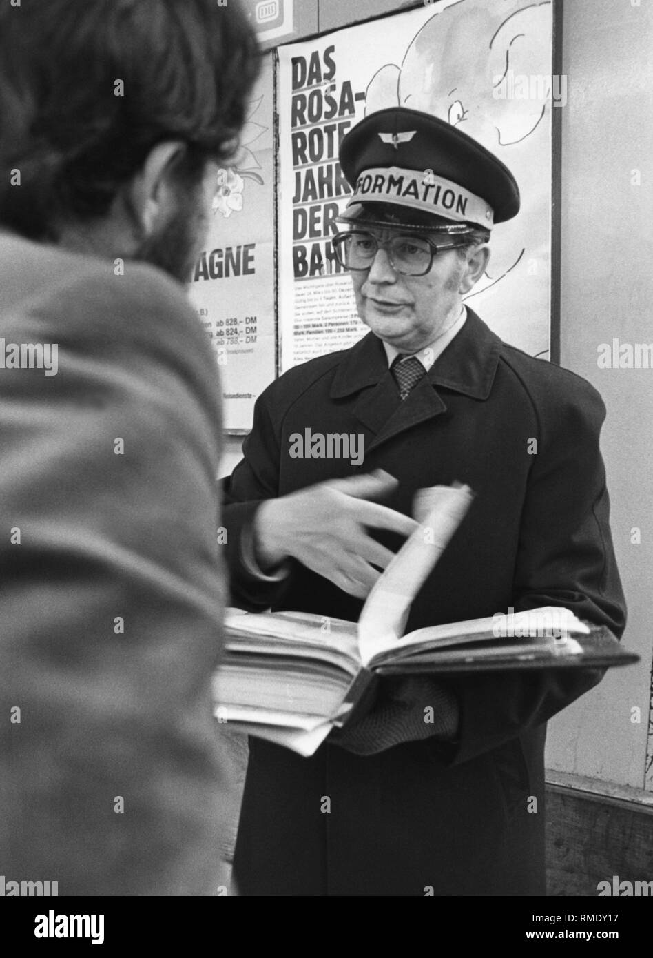 Information officer of the Federal Railways. In the background, a promotional poster of the DB for the 'Rosa-Rote-Jahr'. Stock Photo