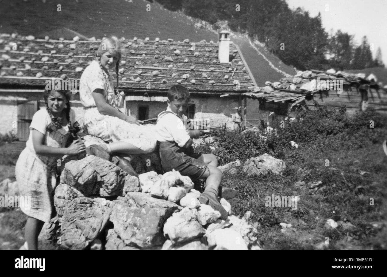 Children in front of an alpine hut near Vorderkaiserfelden during a hike in the Alps. Stock Photo