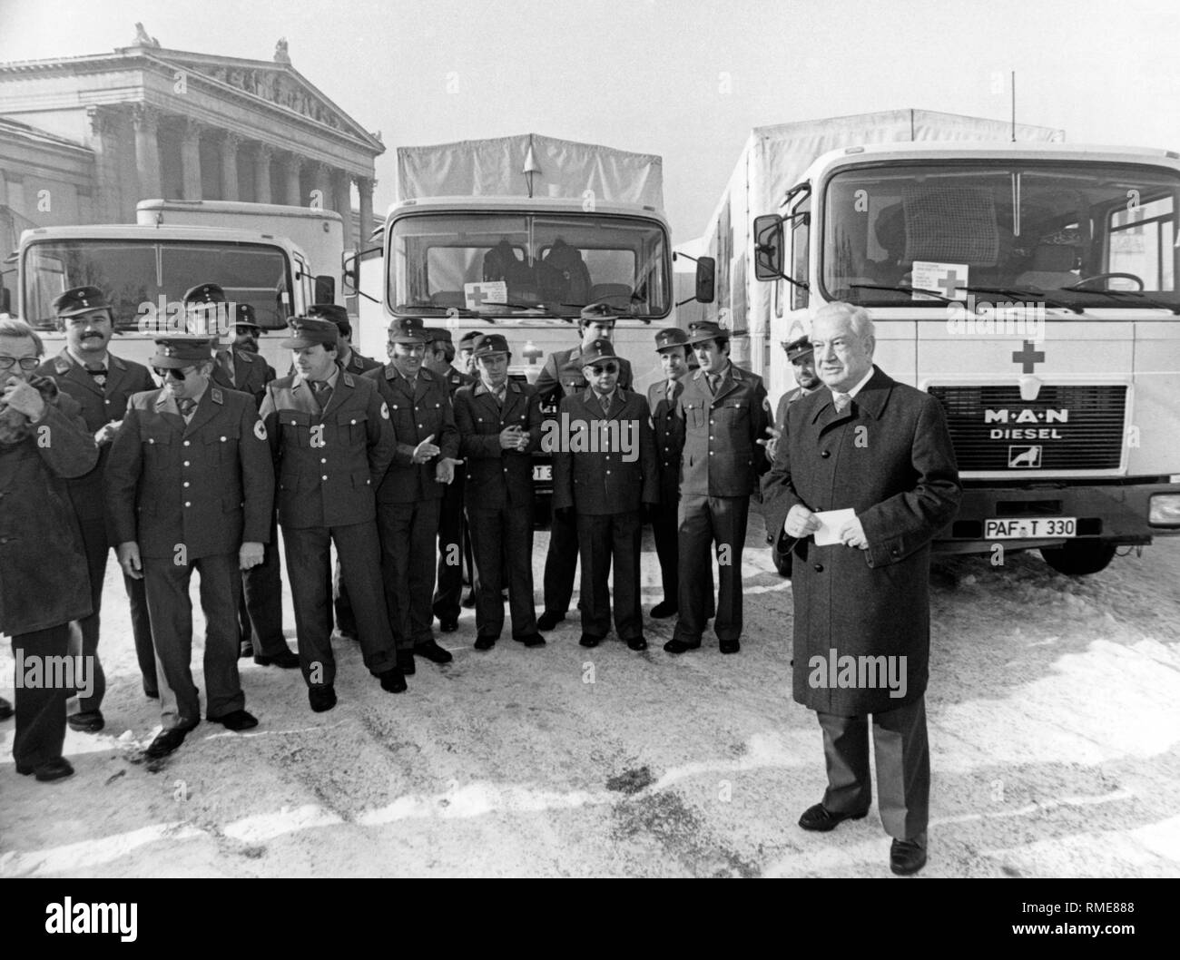 The Bavarian politician and president of the Bavarian Red Cross, Alfons Goppel (r.) in Munich, at the departure of a 100-ton aid convoy to Poland. The convoy, which was put together at the request of the Polish Red Cross, carries basic food, winter clothing, high-quality medicines and general hospital supplies and is accompanied by 17 Red Cross employees (some in the background) and an interpreter. The total value of these 100 tons of relief supplies is about 800,000 marks. It was financed by donations from the Bavarian population. To this were added donations from the industrial sector. Stock Photo