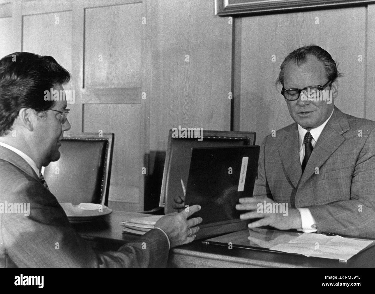 The East German spy Guenter Guillaume presents to Chancellor Willy Brandt a file with documents to be signed, at the beginning of a meeting of the Presidium of the SPD in the City Hall Schoeneberg in Berlin, about a year before his exposure as a GDR spy. Stock Photo