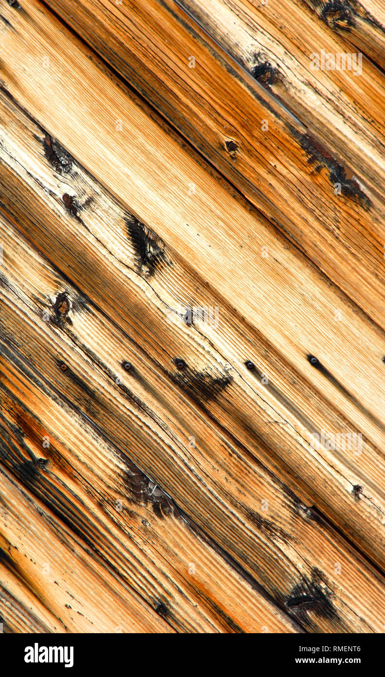 Angled wooden door has slanted boards complete with knots.  Wood grain is cracked and weathered. Stock Photo