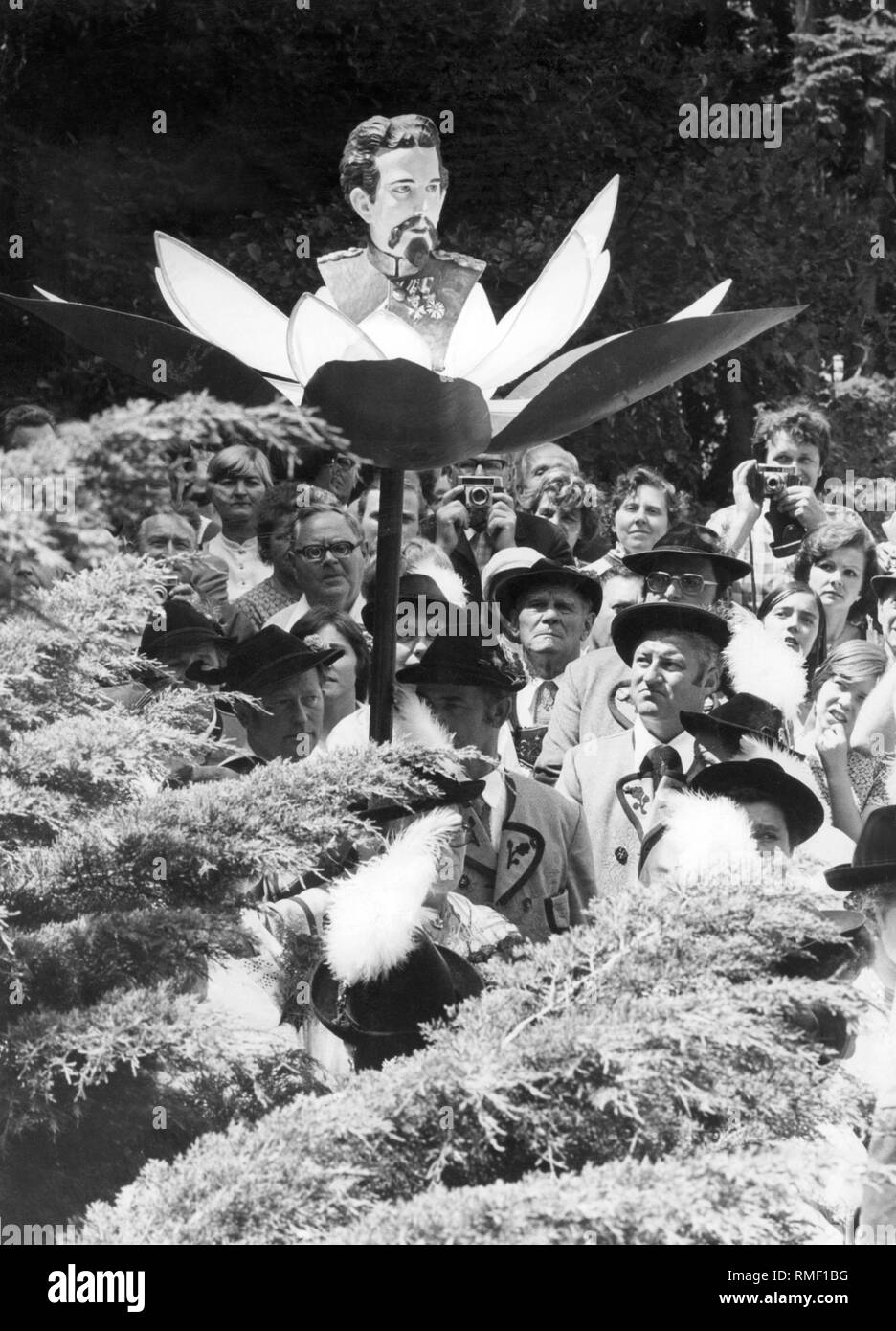 This photograph shows an event of the Koenig-Ludwig-Treuen on the 90th anniversary of the death of the king. They carry a staff with the portrait of King Ludwig II in a bloom through the street. Stock Photo