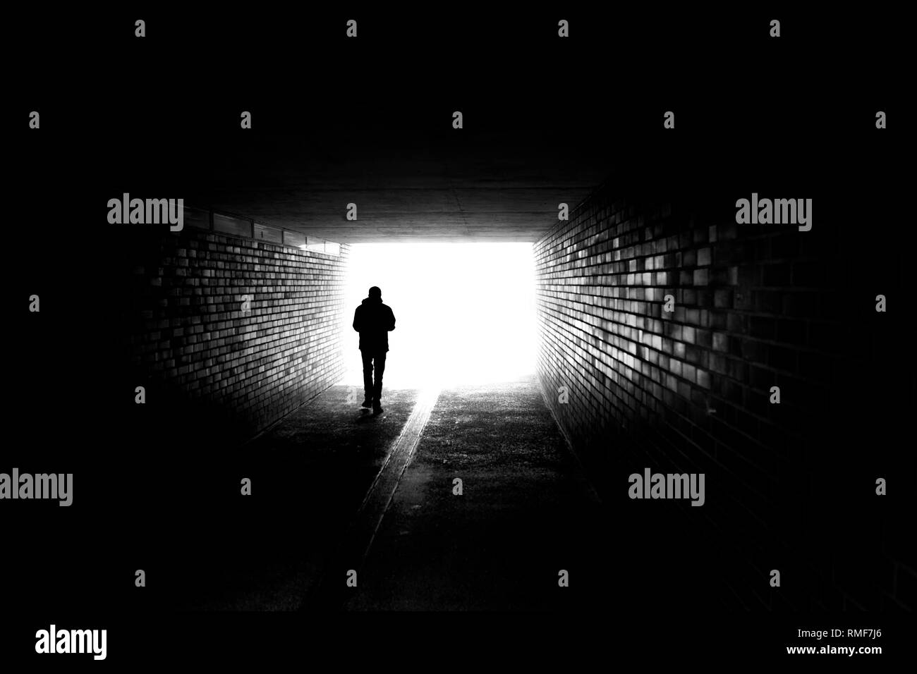 A man walking in a dark tunnel Stock Photo