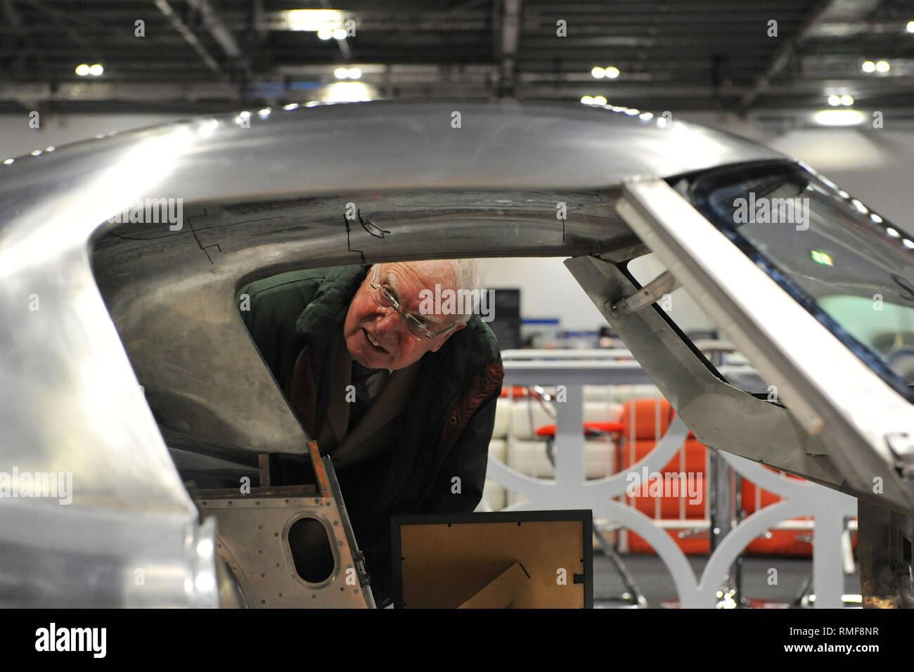 ExCel London, UK. 14th Feb 2019. A man looking at the stripped down shell of a Jaguar E-Type in the process of being restored, on display at the London Classic Car Show which is taking place at ExCel London, United Kingdom. Around 700 of the world's finest classic cars are on display at the show ranging from vintage pre-war tourers to a modern concept cars. The show brings in around 37,000 visitors, ranging from serious petrol heads to people who just love beautiful and classic vehicles. Credit: Michael Preston/Alamy Live News Stock Photo
