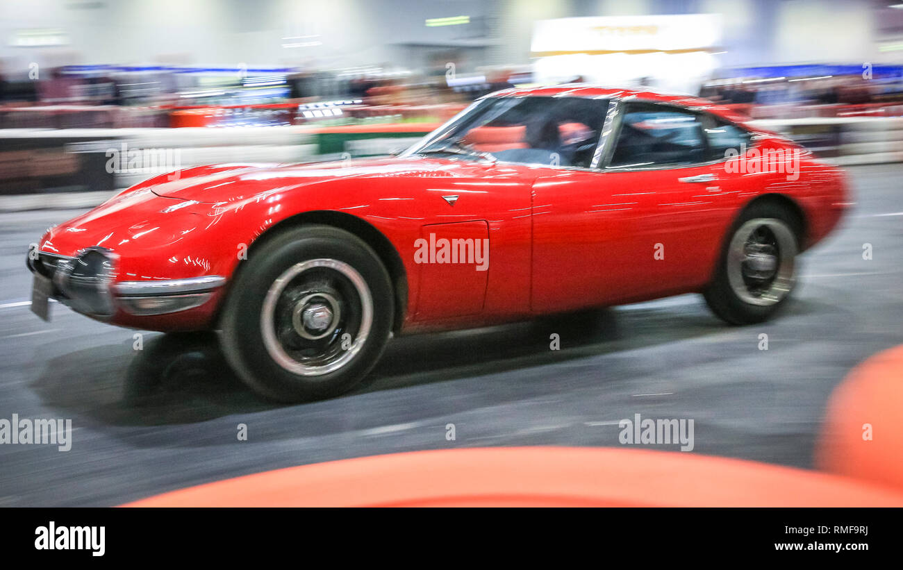 ExCel, London, UK, 14th Feb 2019. A Toyota 2000 GT Classic zooms down the 'Grand Avenue' race track. The London Classic Car Show 2019 opens at ExCel Exhibition Centre in London Docklands. The show  brings together classic car owners, collectors, experts and enthusiast with dealers, manufacturers and car clubs in a celebration of motoring and classic cars. Credit: Imageplotter News and Sports/Alamy Live News Stock Photo