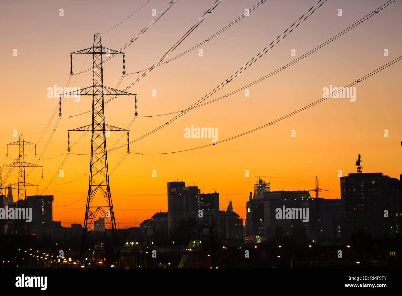 Docklands, London, UK, 14th Feb 2019. UK Weather: Following a beautifully sunny day with blue skies and mild temperatures, the sun sets over East London's Docklands, silhouetting buildings, electricity masts and shipping cranes. Credit: Imageplotter News and Sports/Alamy Live News Stock Photo