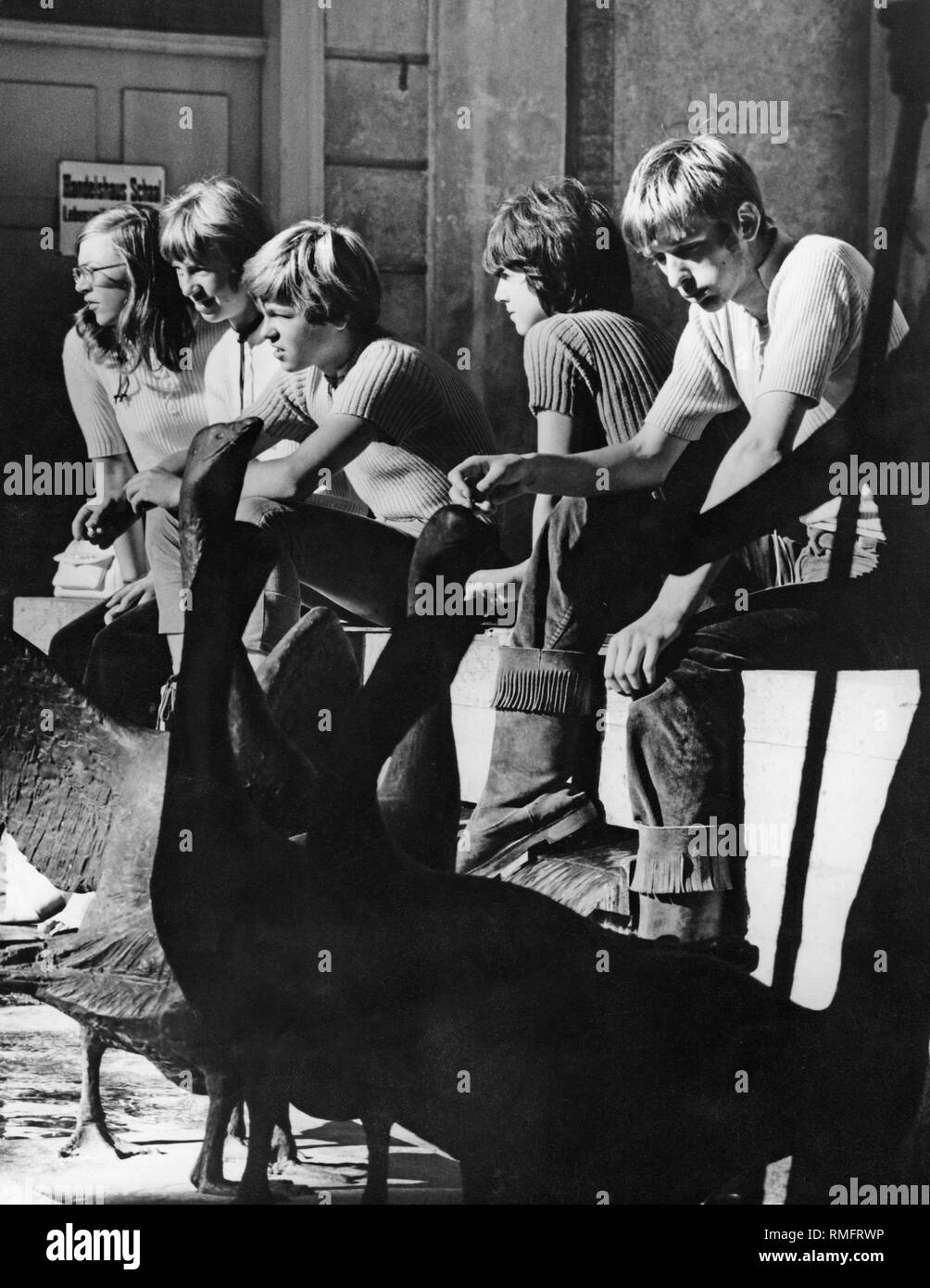 A group of students sits at the Gaenseliesel-Brunnen in Leutkirch in the Allgaeu region of Wuerttemberg. Stock Photo